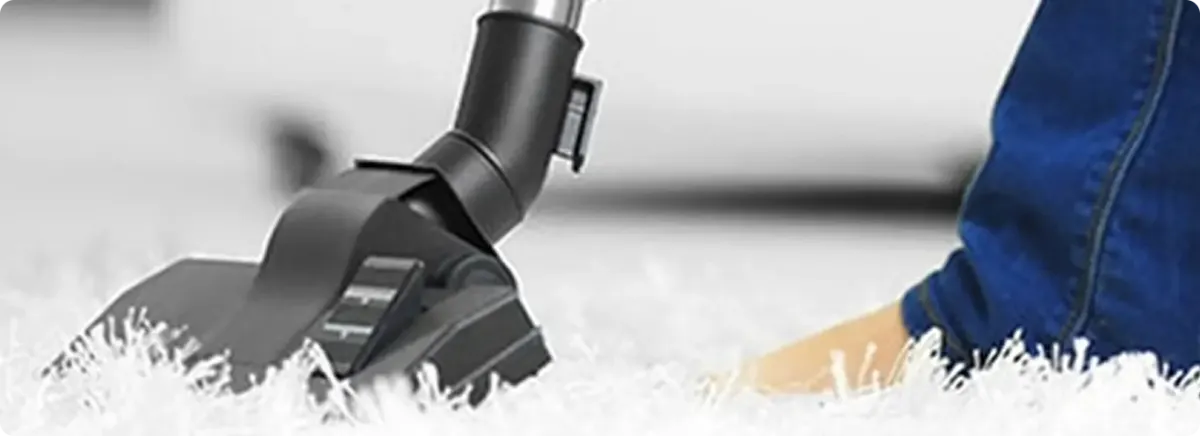 Close-up of a professional vacuuming a white carpet in Loxahatchee.