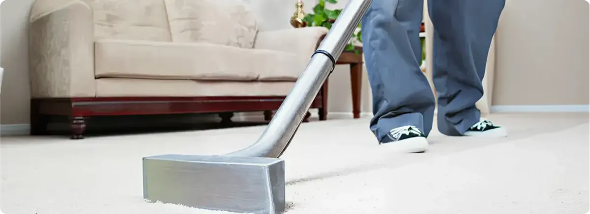 Carpet cleaning technician using a hot-water extraction wand on a light-colored carpet in a living room, West Palm Beach, FL.